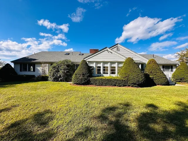 a front view of a house with yard and large trees