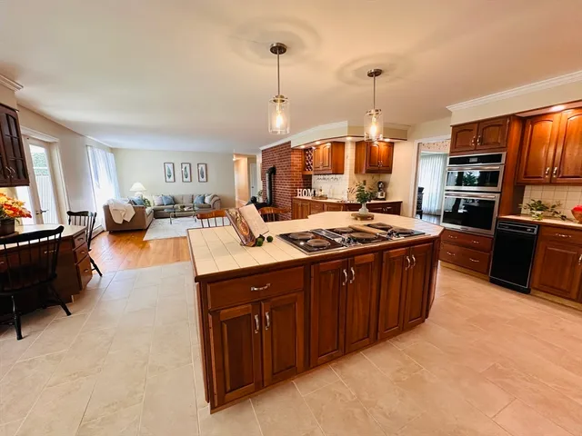 a large kitchen with kitchen island granite countertop a stove top oven a sink a dining table and chairs