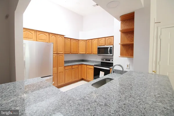 a kitchen with stainless steel appliances granite countertop a refrigerator and a stove top oven