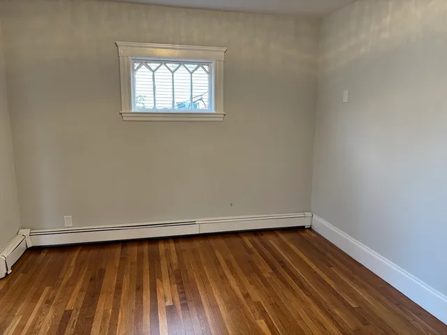 a view of a room with wooden floor and small window