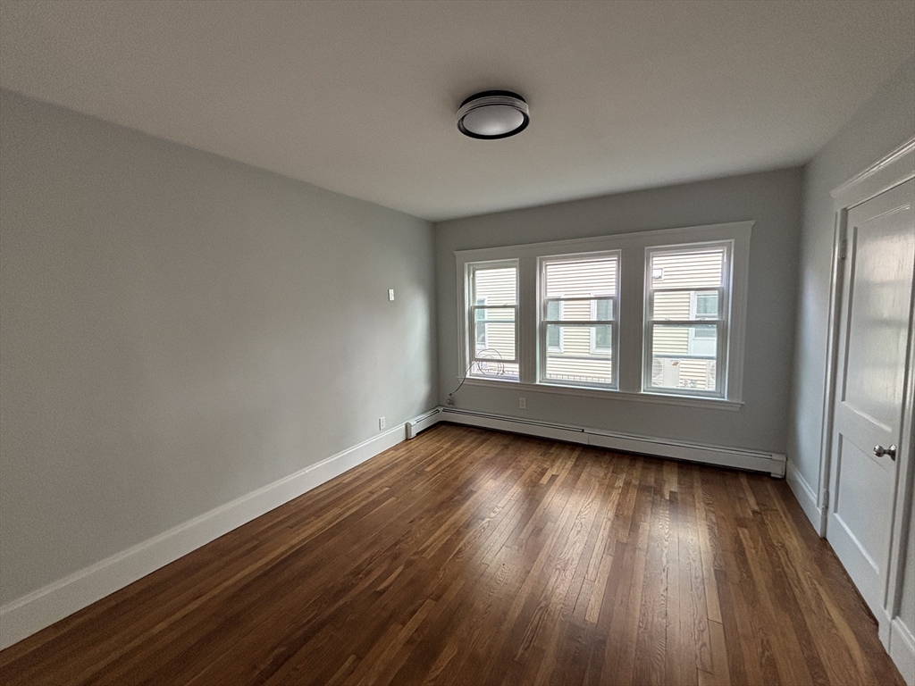 61 Waverly Street, Unit 2 Boston, MA 02135 - Photo 7 of 8 a view of an empty room with wooden floor and a window