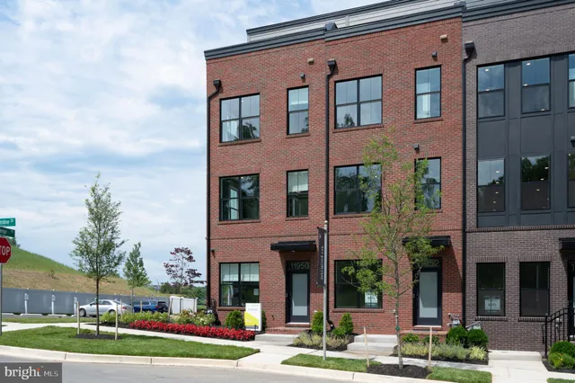 a front view of a building with a yard and plants