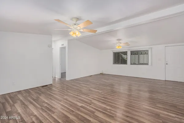 a view of empty room with wooden floor and fan