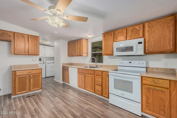 a kitchen with stainless steel appliances granite countertop a stove top oven a sink dishwasher and a microwave oven with wooden floor