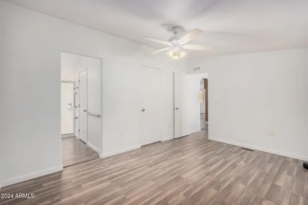 an empty room with wooden floor fan and windows
