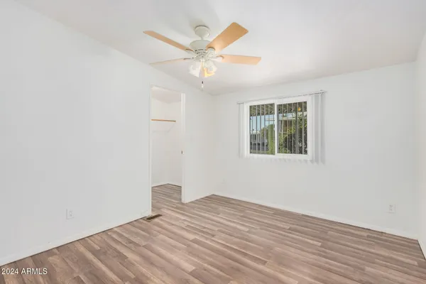 an empty room with wooden floor fan and windows