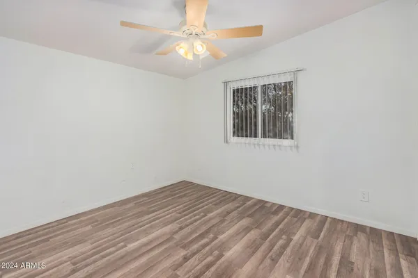 an empty room with wooden floor and fan