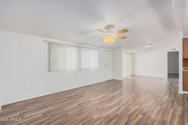 a view of an empty room with wooden floor and windows