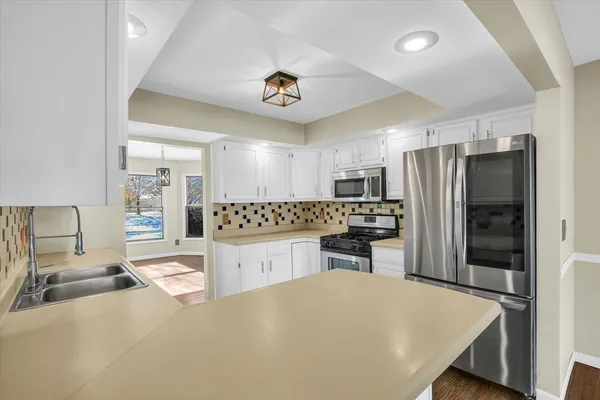 a large kitchen with a refrigerator a sink dishwasher a stove and a refrigerator with wooden floor