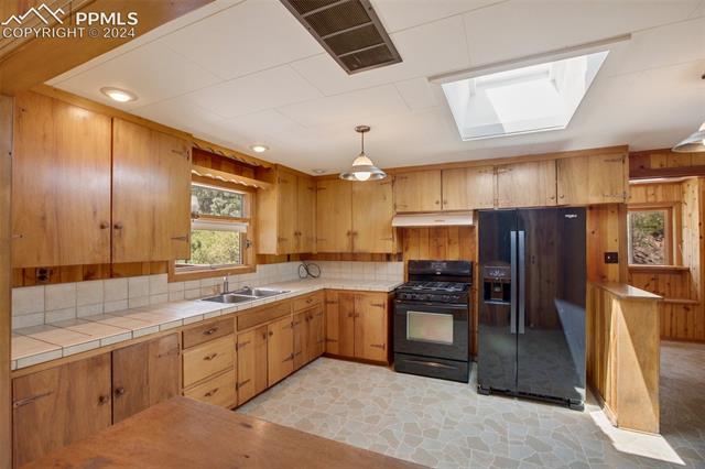 4980 Dodd Road Cascade, CO 80809 - Photo 18 of 48 Kitchen with tasteful backsplash, pendant lighting, black appliances, sink, and a skylight