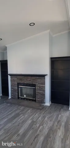 a view of an empty room with wooden floor and a fireplace