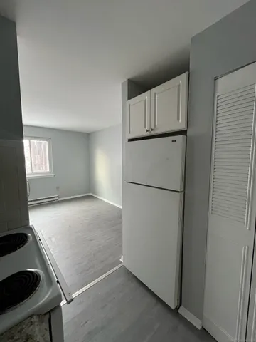 a view of empty room with window and refrigerator