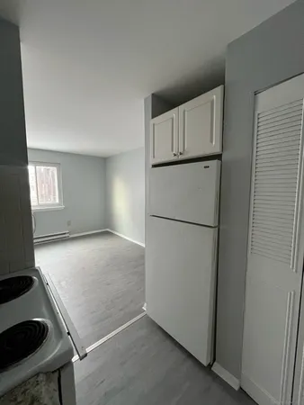 a view of empty room with window and refrigerator
