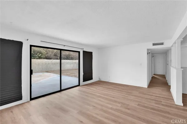 a view of empty room with wooden floor and large window