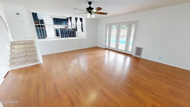 a view of an empty room with bookshelf and wooden floor