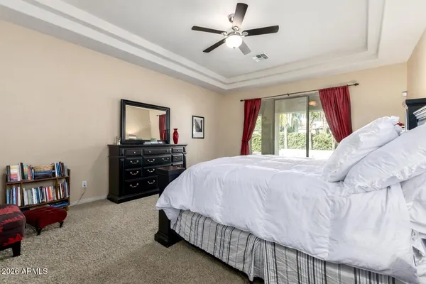 a bedroom with a bed a dresser and a chandelier