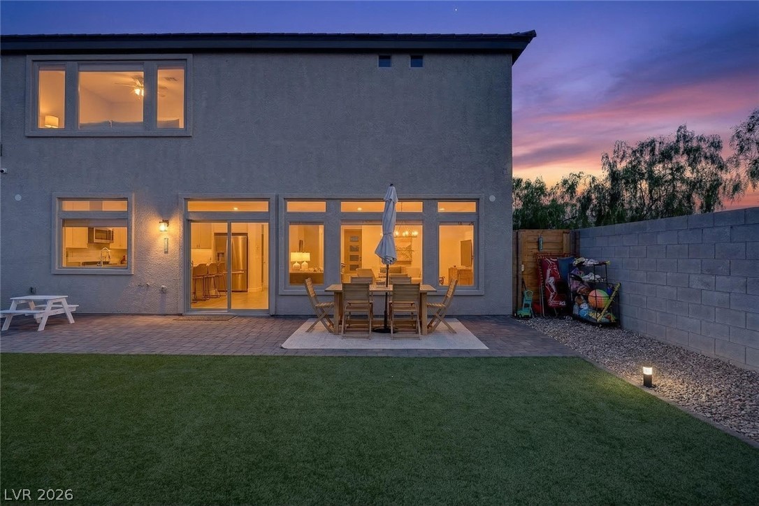 10446 Emerald Rye Street Las Vegas, NV 89183 - Photo 33 of 37 An inviting backyard oasis features a paved patio, lush green lawn, and ample space for outdoor enjoyment.