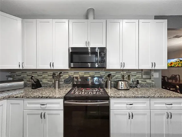 a kitchen with granite countertop a sink stove and cabinets