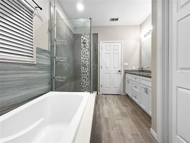 a spacious bathroom with a granite countertop sink a mirror and shower