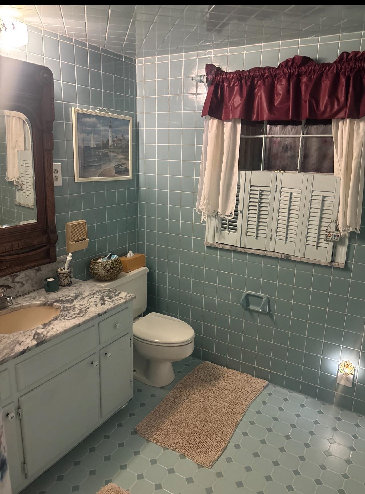 3194 Lammermuir Road Memphis, TN 38128 - Photo 21 of 37 Bathroom featuring floor-to-ceiling blue tile, a white vanity with a marble-finish countertop, and a built-in window with white louvered shutters