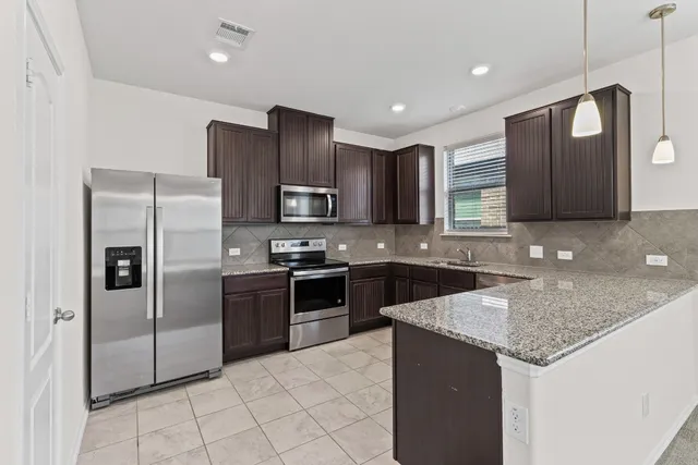 a kitchen with stainless steel appliances granite countertop a refrigerator and a stove top oven