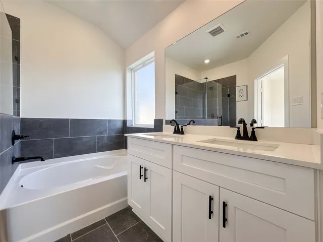 a bathroom with a tub a sink and mirror