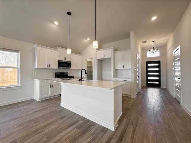 a large kitchen with white cabinets and stainless steel appliances