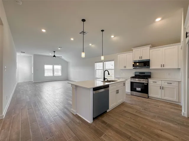 a large kitchen with granite countertop a large counter top and stainless steel appliances