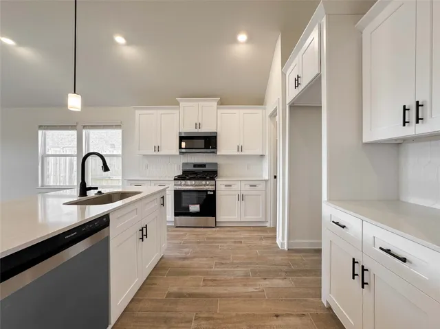 a kitchen with stainless steel appliances granite countertop a sink a stove and a refrigerator