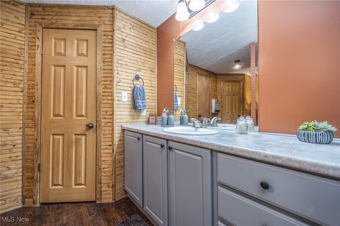 1788 Rosenbush Road Newport, OH 45768 - Photo 25 of 34 Bathroom featuring vanity, a textured ceiling, dark wood-style flooring, and wood walls