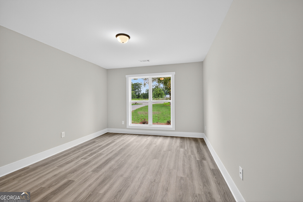 274 Mockingbird Lane, Unit 27 Winder, GA 30680 - Photo 14 of 29 a view of an empty room with wooden floor and a window