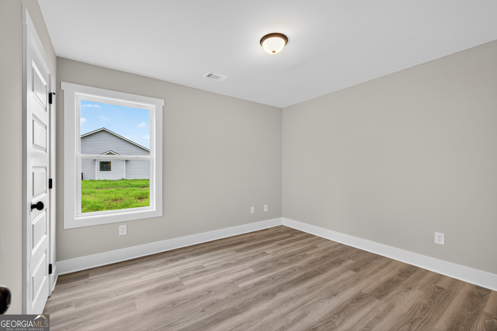 274 Mockingbird Lane, Unit 27 Winder, GA 30680 - Photo 18 of 29 a view of an empty room with wooden floor and a window