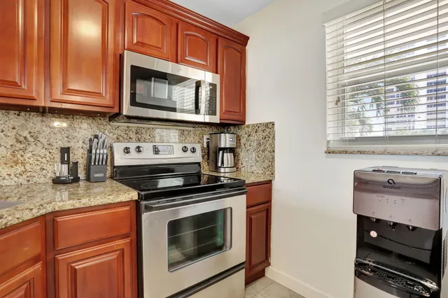a kitchen with granite countertop a stove top oven microwave and cabinets
