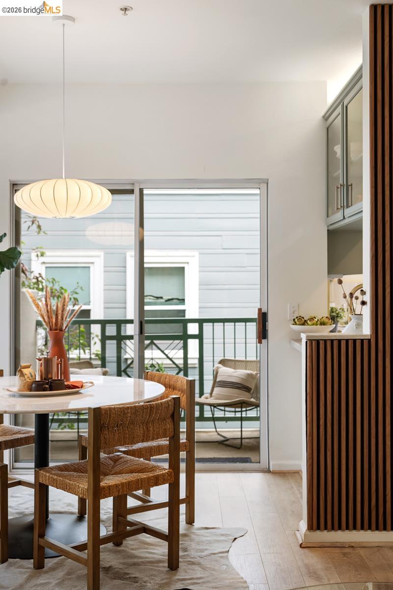 2029 Channing Way, Unit 3D Berkeley, CA 94704 - Photo 10 of 54 Dining area featuring wood-finish flooring, a white circular table, and a sliding glass door opening to a balcony with green metal railings