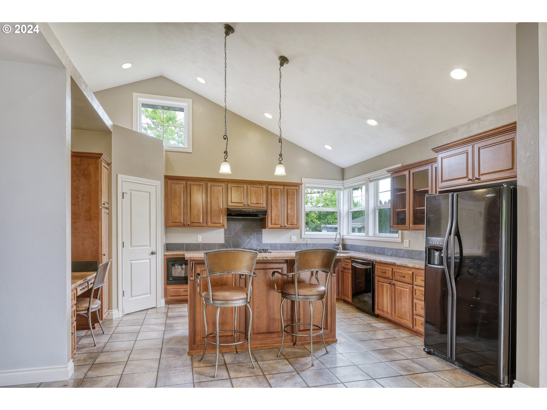 3349 Roanoke Avenue Eugene, OR 97408 - Photo 10 of 36 a kitchen with stainless steel appliances kitchen island granite countertop a refrigerator a stove a sink a dining table and chairs with wooden floor