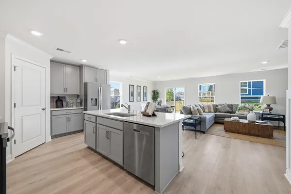 a kitchen with stainless steel appliances a refrigerator a stove a sink cabinets and a dining table with wooden floor