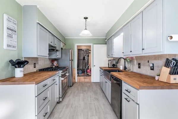 a kitchen with stainless steel appliances granite countertop a stove top oven a sink a refrigerator and white cabinets
