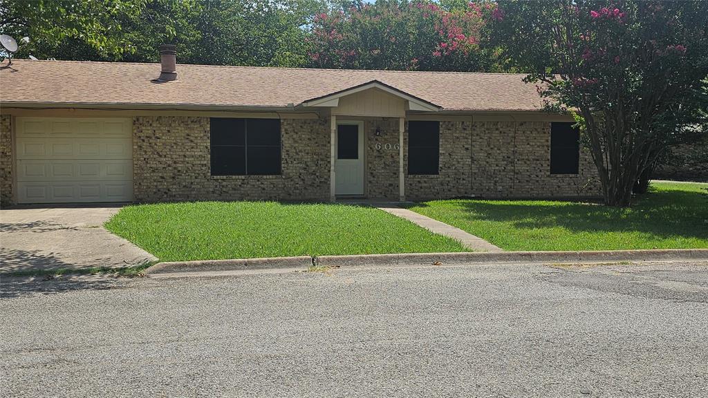 a view of a white house with a small yard and large trees