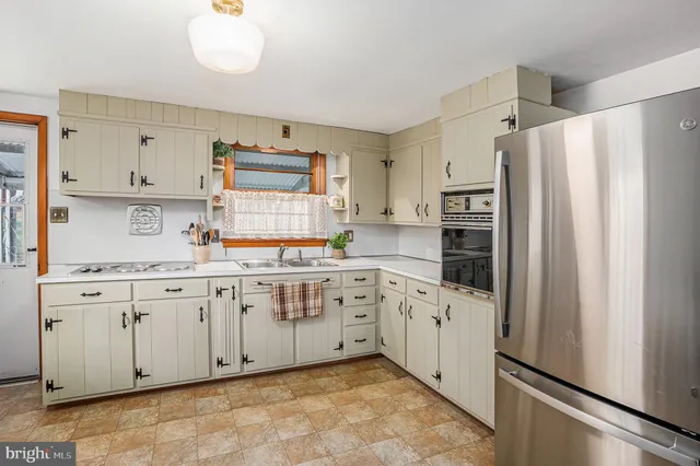 a kitchen with granite countertop white cabinets and refrigerator