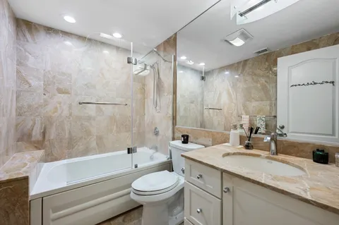a bathroom with a double vanity sink toilet mirror and bathtub