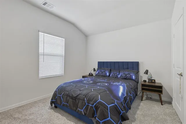 a bedroom with a bed and a computer on a desk next to a window