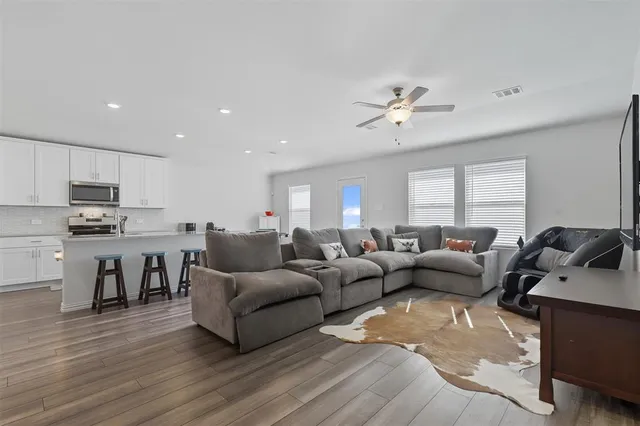 a living room with furniture kitchen view and a wooden floor
