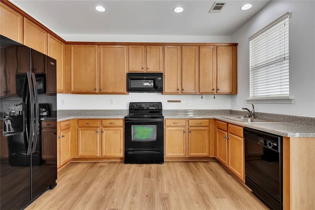 3972 Cutler Donahoe Way Cumming, GA 30040 - Photo 12 of 46 a kitchen with granite countertop wooden cabinets a stove top oven and stainless steel appliances