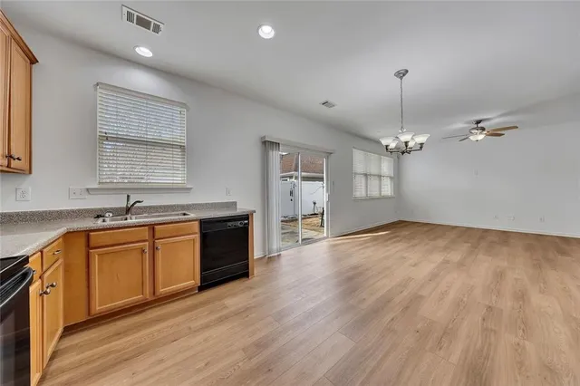 a large kitchen with stainless steel appliances granite countertop a sink dishwasher a stove and white countertops with wooden floor