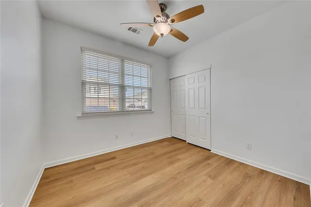 an empty room with wooden floor fan and windows