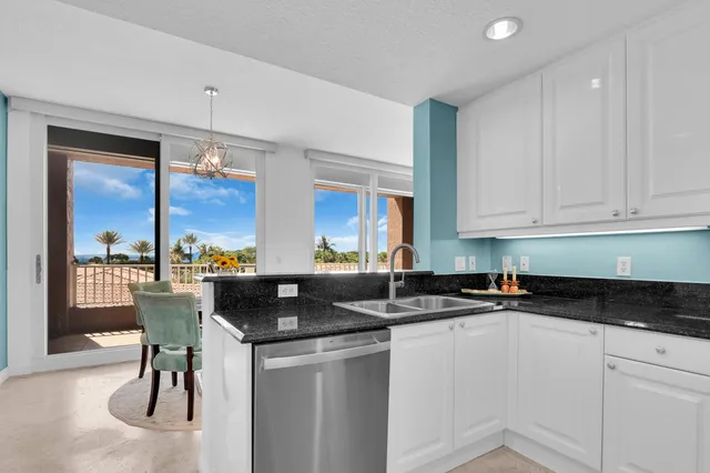 a kitchen with stainless steel appliances granite countertop a refrigerator a stove a sink and white cabinets with wooden floor