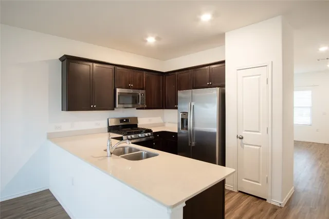 a kitchen with a refrigerator a microwave a sink and cabinets