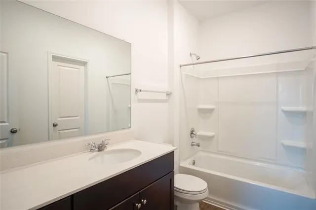 a bathroom with a granite countertop sink toilet a large mirror a shower and a bathtub