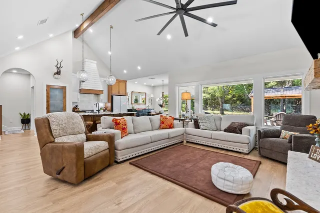 a living room with furniture kitchen view and a large window