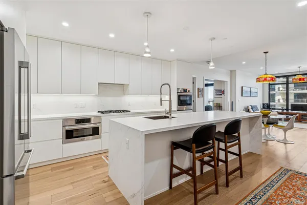 a kitchen with stainless steel appliances kitchen island granite countertop a stove a sink a refrigerator and chairs